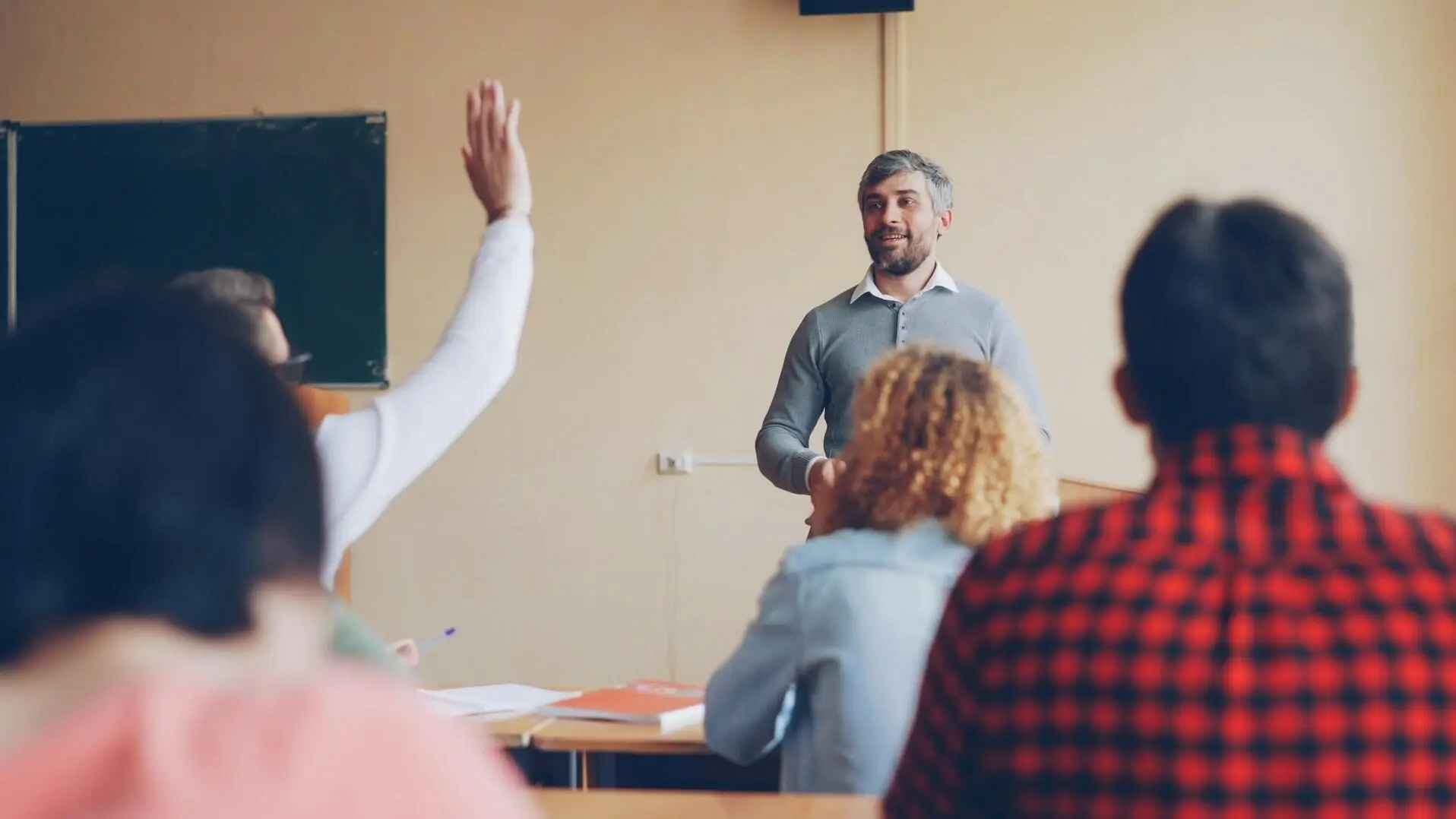 FAQ Schüleraustausch Lehrer Lehrer, der den Schülern im Klassenzimmer eine Frage stellt.