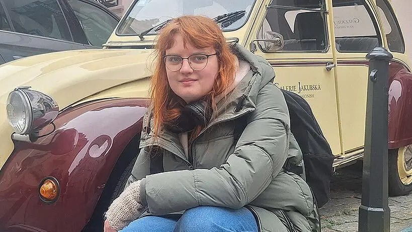 Austauschschülerin Hanna kniet vor einem Oldtimer einer tschechischen Galerie