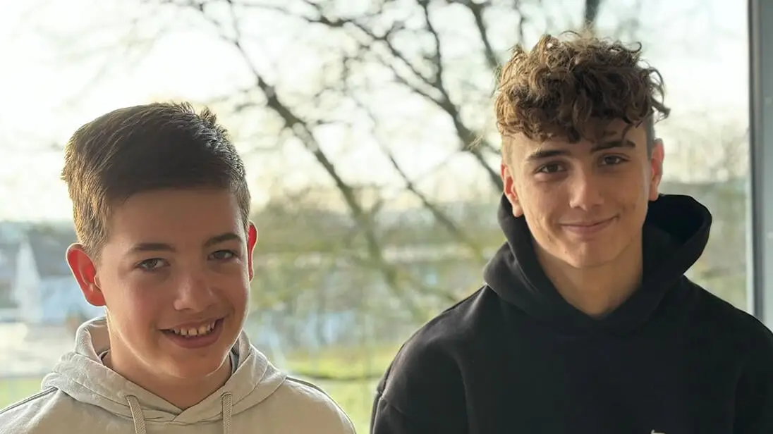 Tim und Gregor stehen vor einem Fenster in der Realschule Wemding mit Blick auf die Bäume